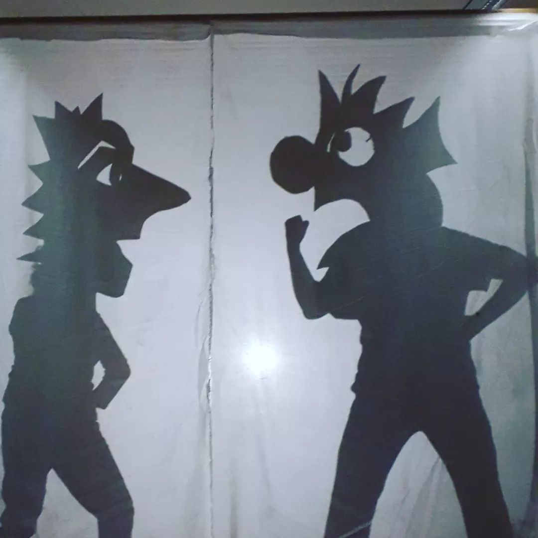 2 Masken diskutieren hinter einer Schattenwand